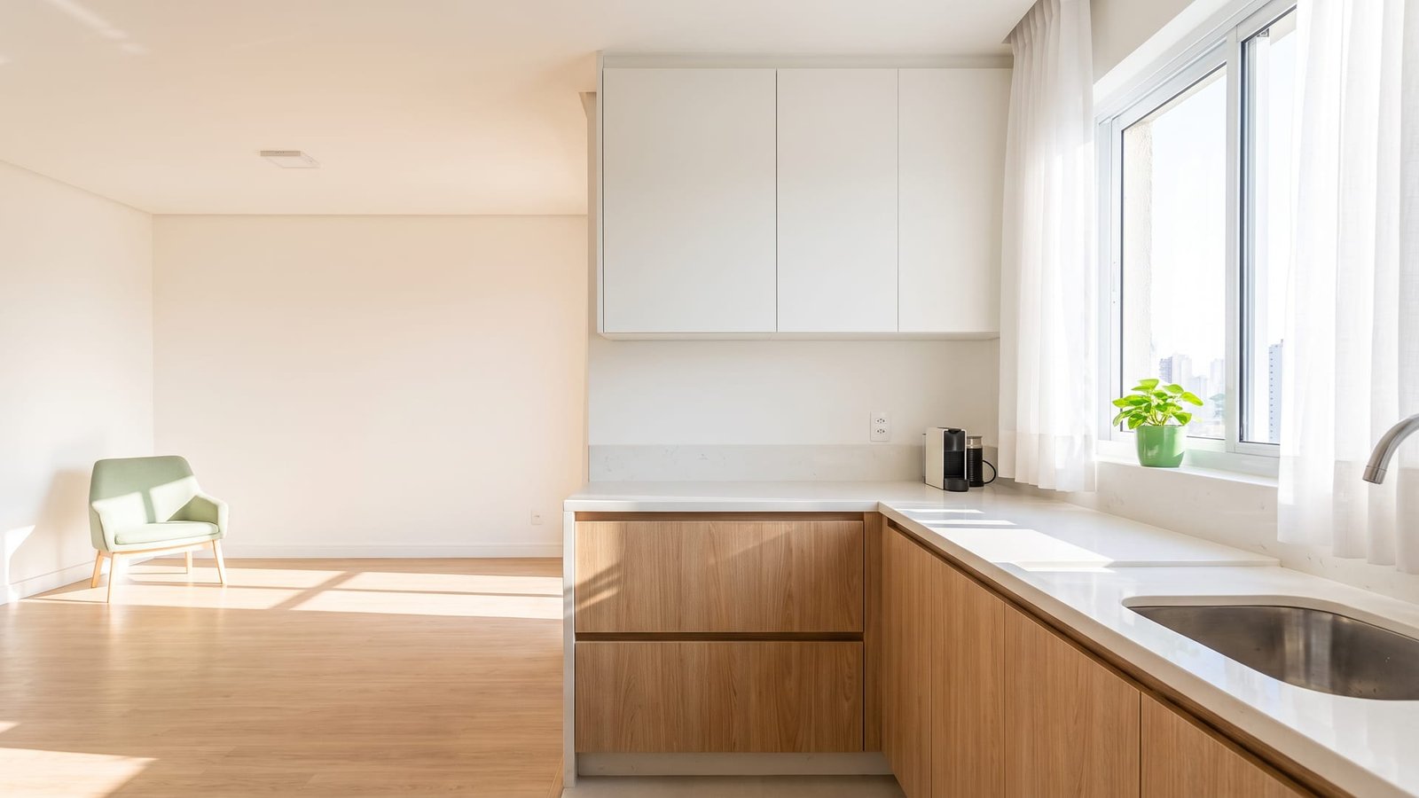 Cozinha compacta de apartamento em branco fosco e carvalho claro, com luz da manhã